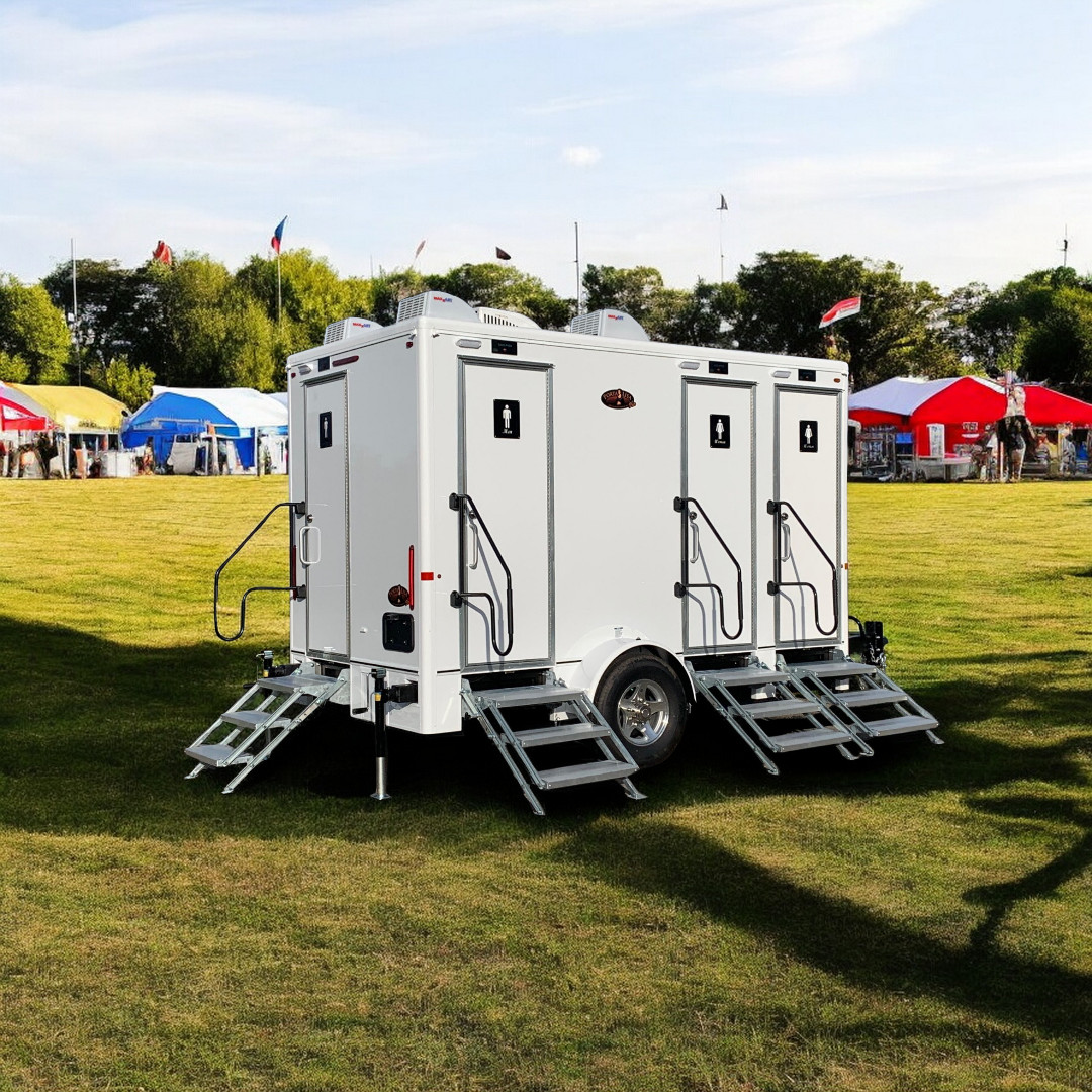 A luxurious 4 stall bathroom trailer with elegant interior and high-end fixtures at an outdoor
              festival venue